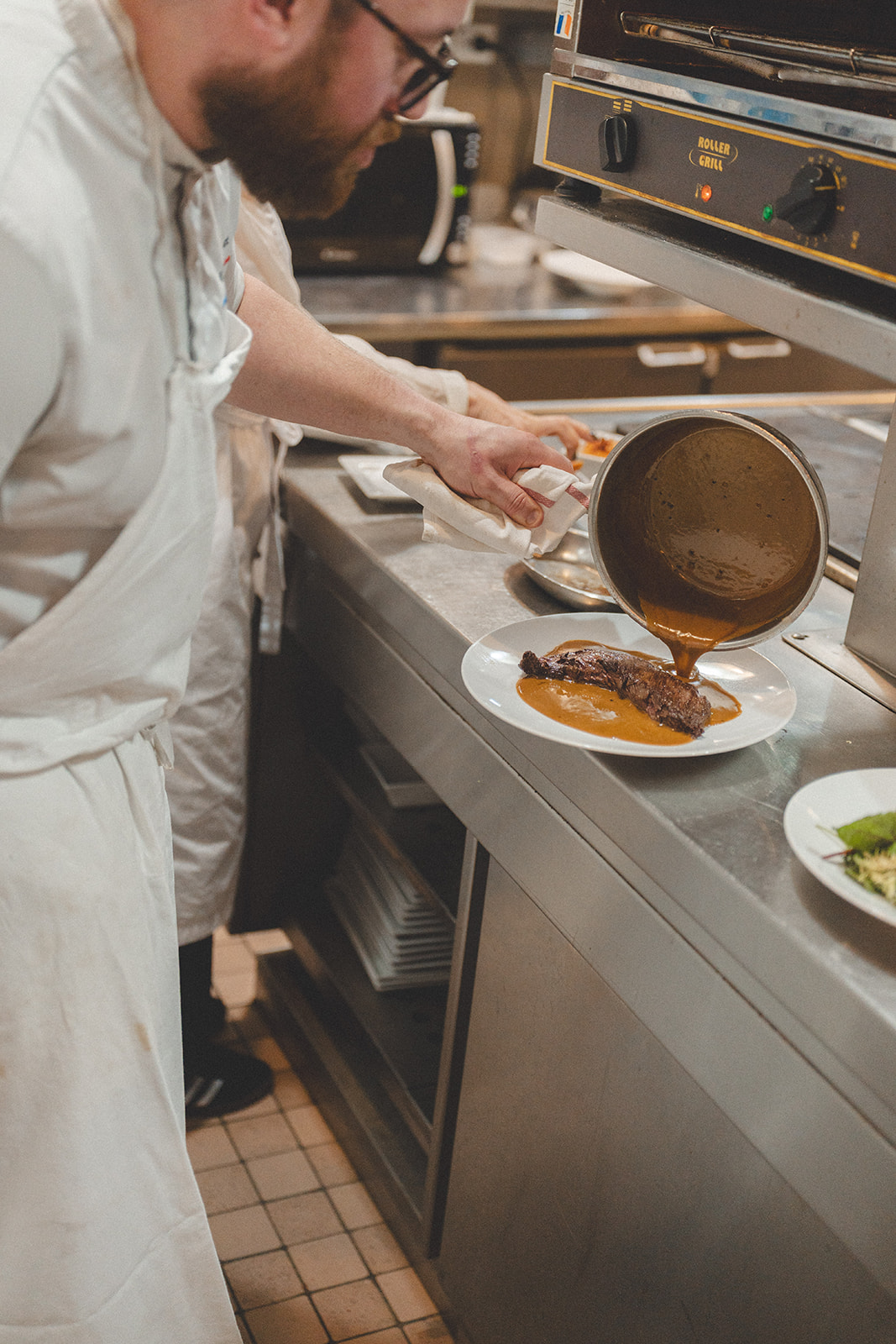 Sauce versée sur une pièce de bœuf en cuisine, côte de bœuf Paris 6e chez Joséphine Chez Dumonet